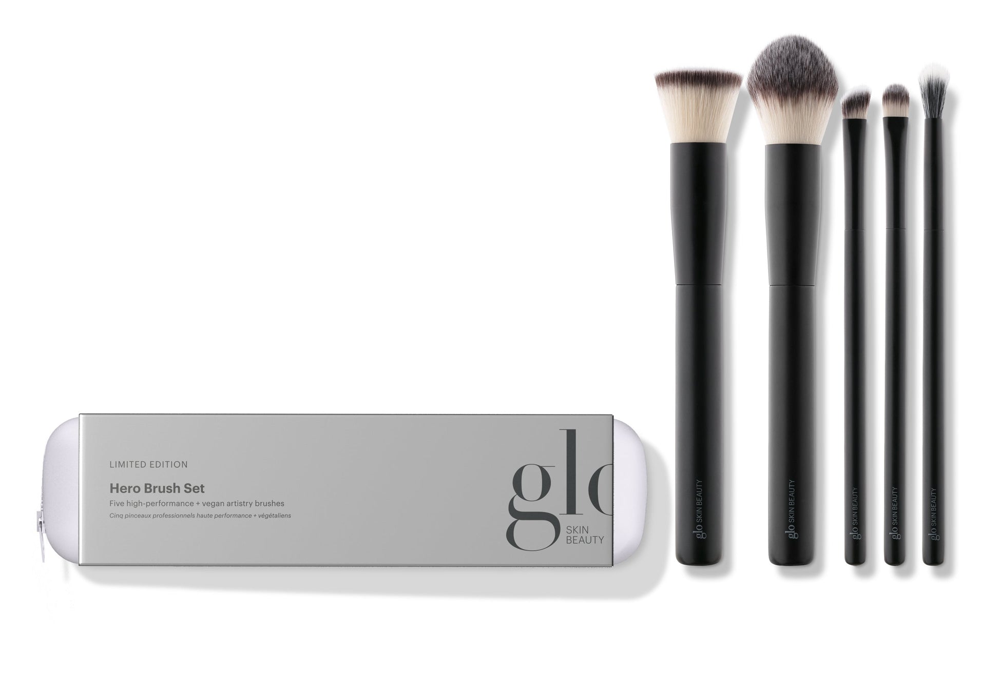 A collection of five high-performance, vegan makeup brushes displayed alongside their packaging which reads 'hero brush set'. The brushes are designed for various makeup applications including powder, concealer, foundation, eyeshadow, and eyeliner.