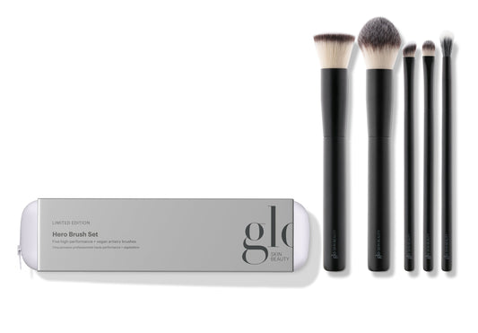 A collection of five high-performance, vegan makeup brushes displayed alongside their packaging which reads 'hero brush set'. The brushes are designed for various makeup applications including powder, concealer, foundation, eyeshadow, and eyeliner.